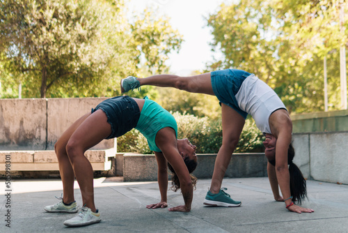 amigas practicando capoeira, flexibilidad y patadas en la ciudad en un día soleado.