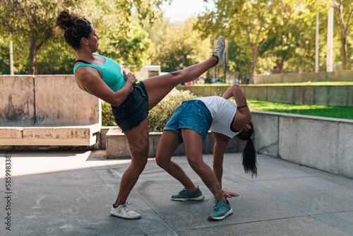 bellas mujeres deportistas practicando patadas de capoeira en la ciudad en un día soleado.