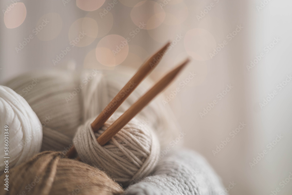 Cozy homely atmosphere. Female hobby knitting. Yarn in neutral shades in a soft basket of white and brown cord. Cozy homely atmosphere. Female hobby knitting. Yarn in neutral shades in a soft basket of white and brown cord.