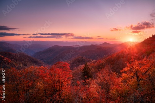 Scenic view of the sunset over an autumnal mountain forest under colorful dusk sky