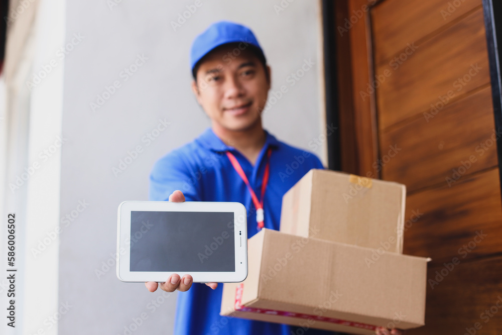Smiling deliveryman in blue uniform with cap holds parcels to send while showing blank screen of smartphone for mock up. Smiling deliveryman in blue uniform with cap holds parcels to send while showing blank screen of smartphone for mock up.