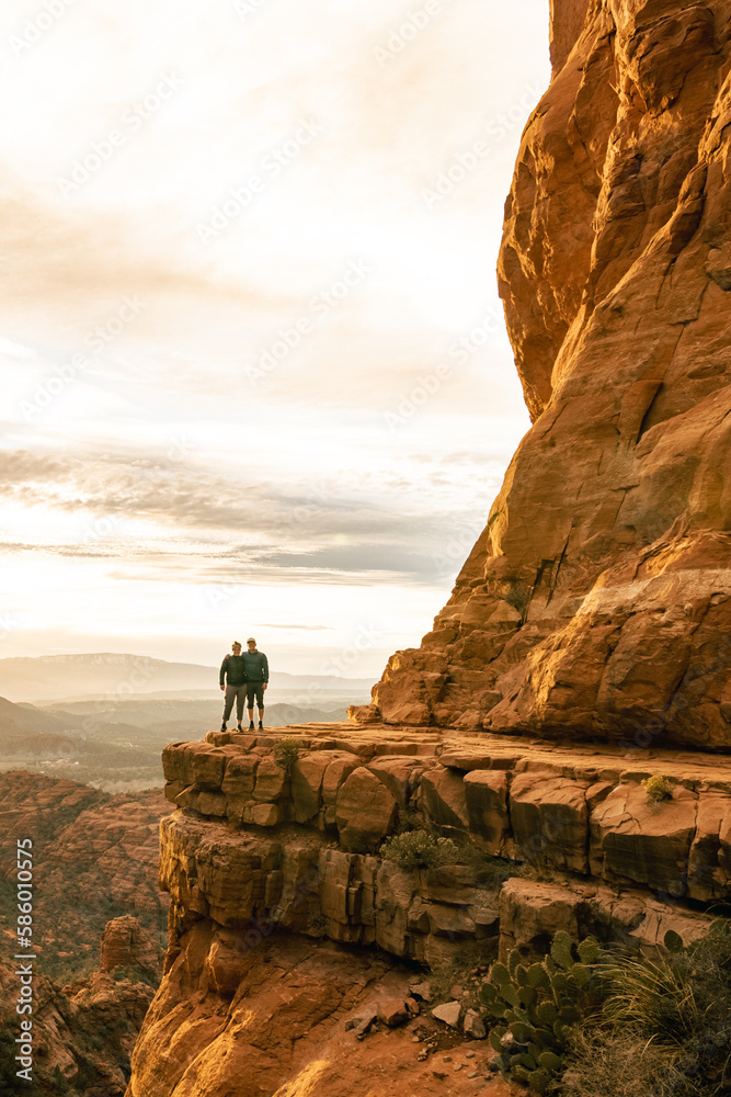 Young couple side by side are on top of Cathedral Rock in Sedona pose for vertical photo.