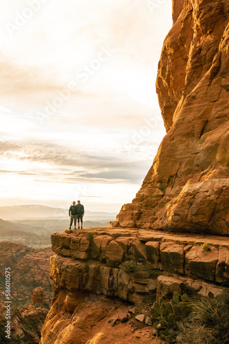 Young couple side by side are on top of Cathedral Rock in Sedona pose for vertical photo.