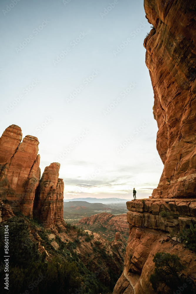 Wide angle vertical view of woman standing at sunset in Sedona Arizona from Cathedral Rock Viewpoint.