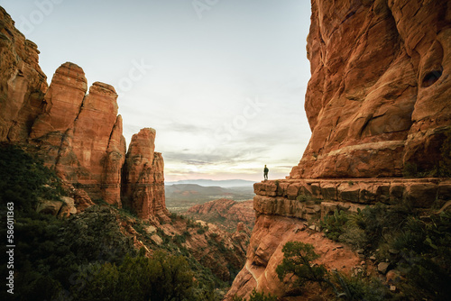 Wide angle view of woman standing at sunset from Cathedral Rock in Sedona.