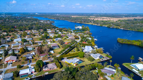 Real Estate Homes on a River in Bonita Springs, Florida Lined by Foliage and Luxury Real Estate, Featuring Clear Sky and Light Clouds