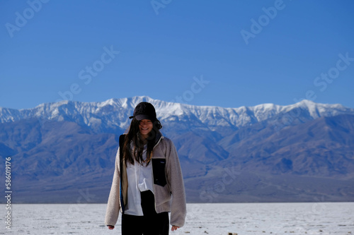 woman standing in salt field in front of mountains