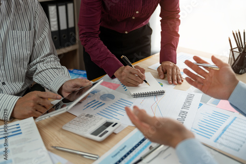Group of businessmen or financial analysts working together use a calculator Plan and record the summary information. management into a book to analyze financial investment plans.