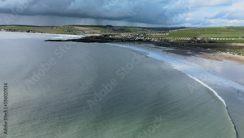 An aerial reveal flying backwards over coastline in Ireland with dramatic skies and sandy beach photo