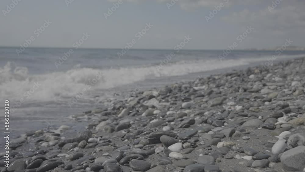 Waves crashing into rocky beach on a sunny day in slowmotion LOG
