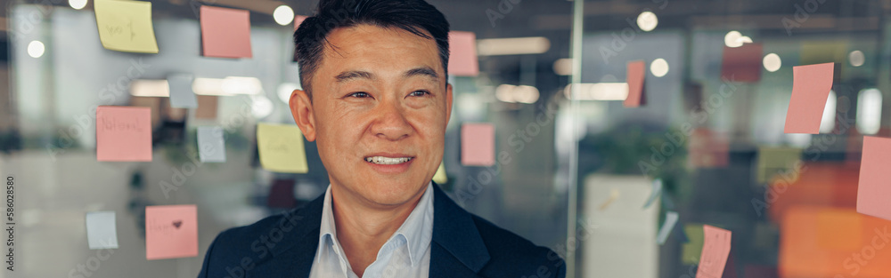Portrait of handsome asian businessman in suit standing in office and looking away Portrait of handsome asian businessman in suit standing in office and looking away