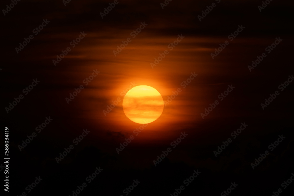 Sunset sky with clouds and bright orange sun in the evening.