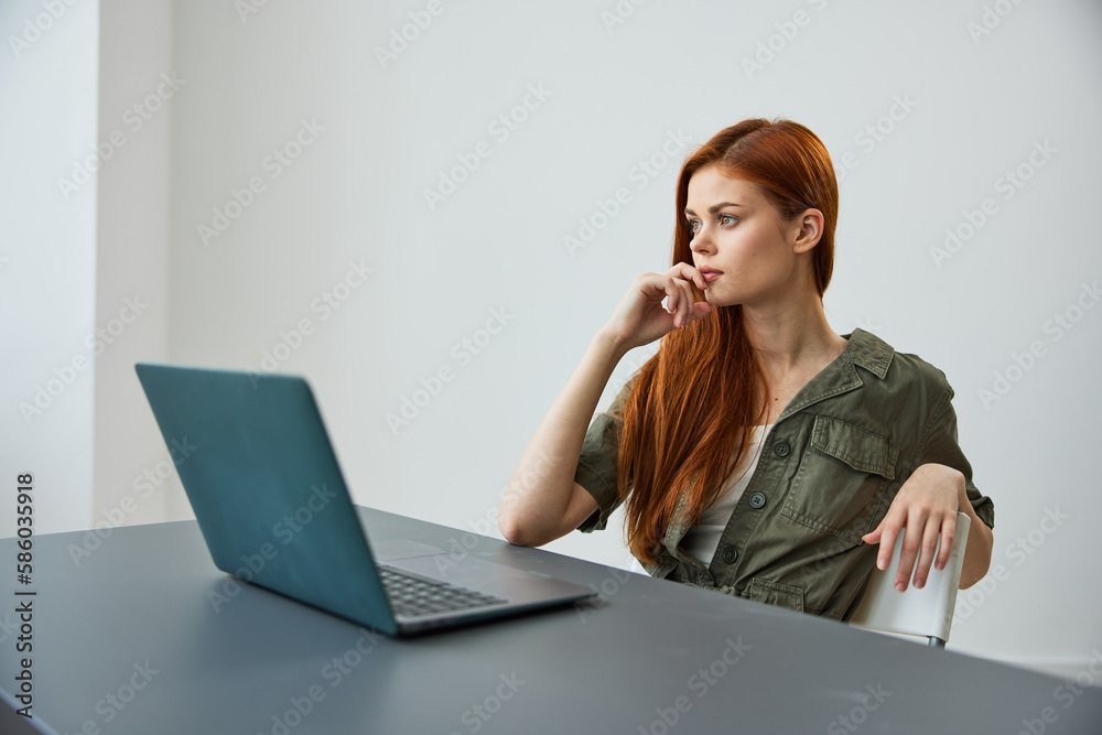 a woman in a large bright room sits at a laptop and seriously thinks about her work a woman in a large bright room sits at a laptop and seriously thinks about her work
