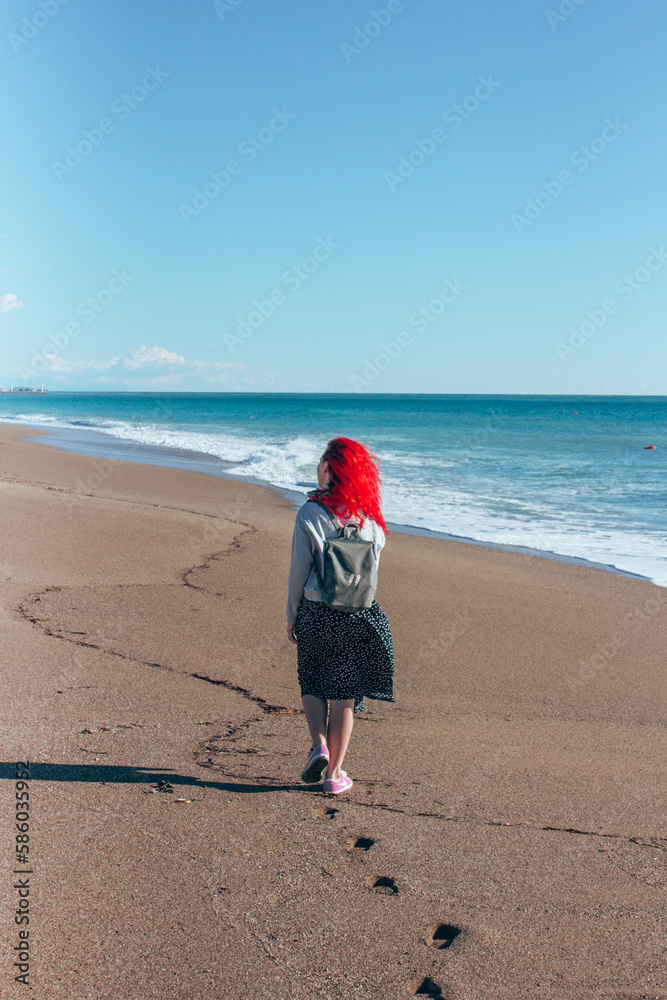 Girl with red hair walking on the beach turkey and looking into the distance