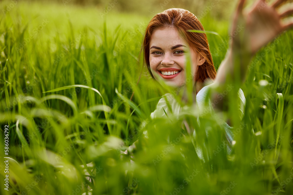 portrait of a broadly smiling woman sitting in tall grass and holding out her hands to the camera portrait of a broadly smiling woman sitting in tall grass and holding out her hands to the camera