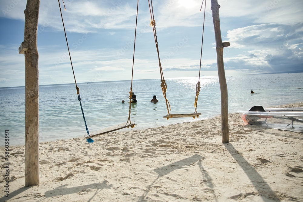 Gorgeous idyllic beach of Siquijor in the Philippines with wooden swings in the center.