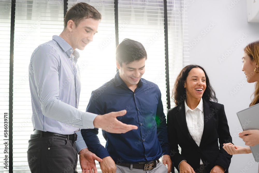 Group of young Asian and multiethnic business man and business woman standing while having a friendly conversation and discussion during break time in modern office Group of young Asian and multiethnic business man and business woman standing while having a friendly conversation and discussion during break time in modern office
