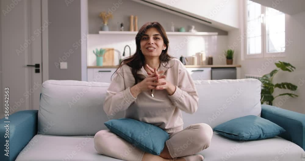 Pretty caucasian woman records video sitting on sofa in living room of cozy apartment. Female blogger presses record button on her phone, view from phone's camera. Blogger records conversational video Pretty caucasian woman records video sitting on sofa in living room of cozy apartment. Female blogger presses record button on her phone, view from phone's camera. Blogger records conversational video