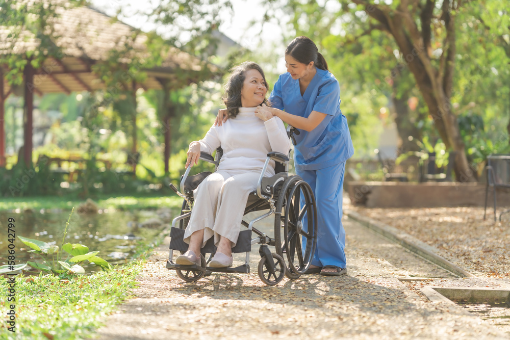 Young asian care helper with asia elderly woman on wheelchair relax together park outdoors to help and encourage and rest your mind with green nature. Young asian care helper with asia elderly woman on wheelchair relax together park outdoors to help and encourage and rest your mind with green nature.
