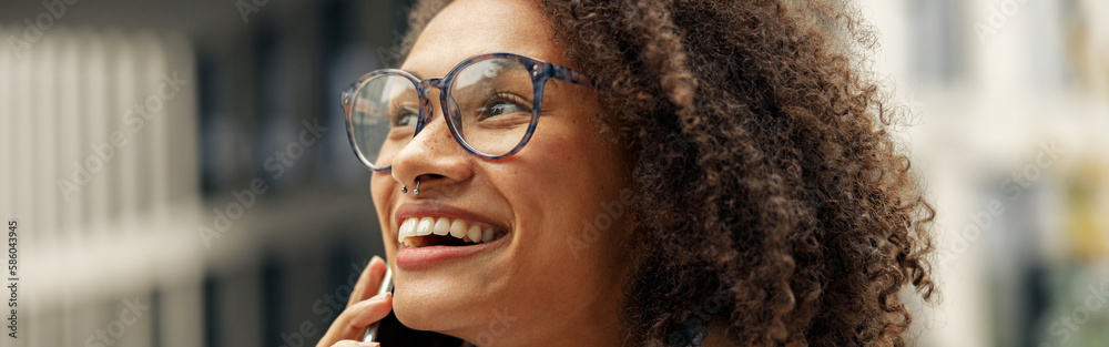 Close up of afro american woman wearing glasses talking phone with friends during city walking Close up of afro american woman wearing glasses talking phone with friends during city walking