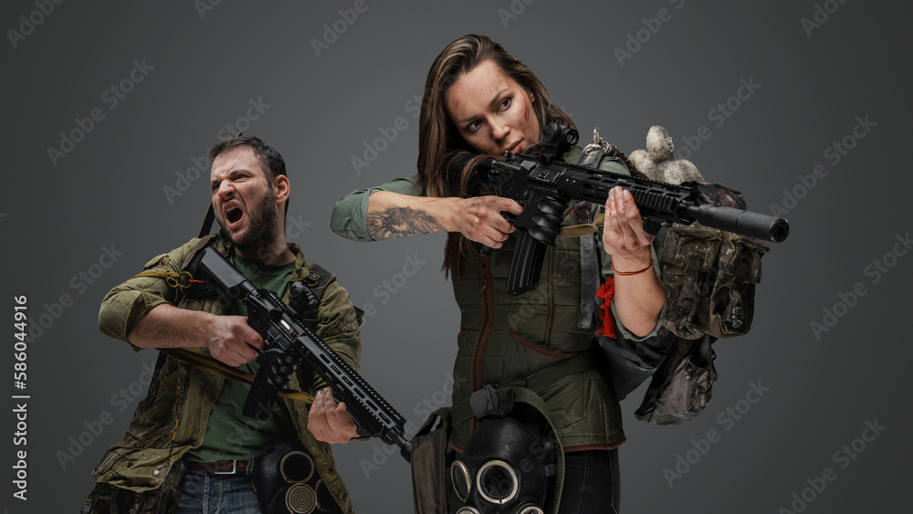 Studio shot of woman aiming rifle and screaming guy in setting of post apocalypse. - obrazy, fototapety, plakaty 