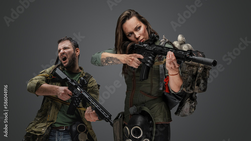 Studio shot of woman aiming rifle and screaming guy in setting of post apocalypse.