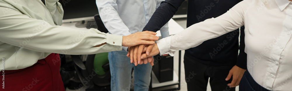 Four colleagues give the low five in the office. Close-up of the hands of office workers. Four colleagues give the low five in the office. Close-up of the hands of office workers.