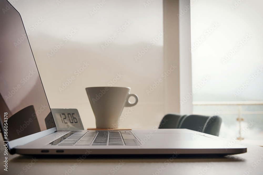 Empty workplace with a modern laptop, coffee cup and digital clock. Coffee break concept Empty workplace with a modern laptop, coffee cup and digital clock. Coffee break concept
