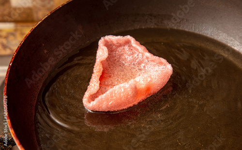 Red chips are fried in oil in a frying pan