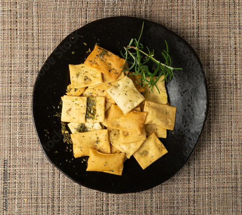 Pita Chips Pile on Black Plate, Small Wheat Tortillas, Crunchy Flat Bread, Spicy Mediterranean Wheat Snack photo