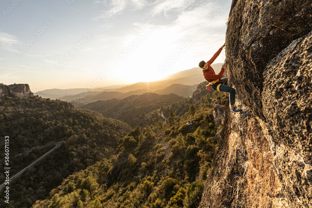 Obraz premium man climbing at sunset in the mountains with the forest in the background, copy space, business, security, trust