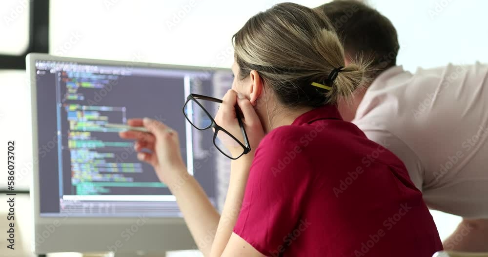 Programmers discuss code structure looking at monitor in office. Project manager with engineer checks up digital data. Software development technology Programmers discuss code structure looking at monitor in office. Project manager with engineer checks up digital data. Software development technology
