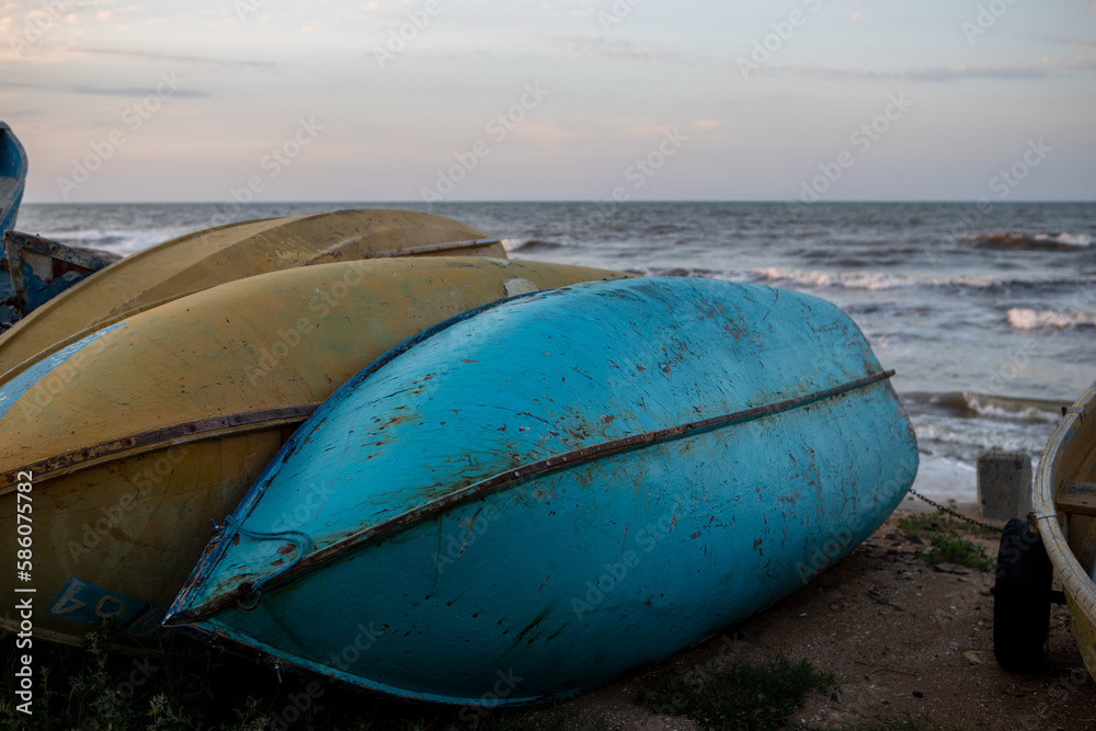 old overturned fishing boats on the seashore during sunset on the background of the sea. old overturned fishing boats on the seashore during sunset on the background of the sea.