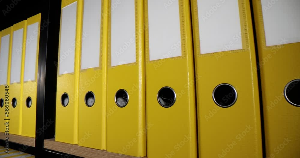 Yellow ring binders put in row on shelf of rack in office Yellow ring binders put in row on shelf of rack in office
