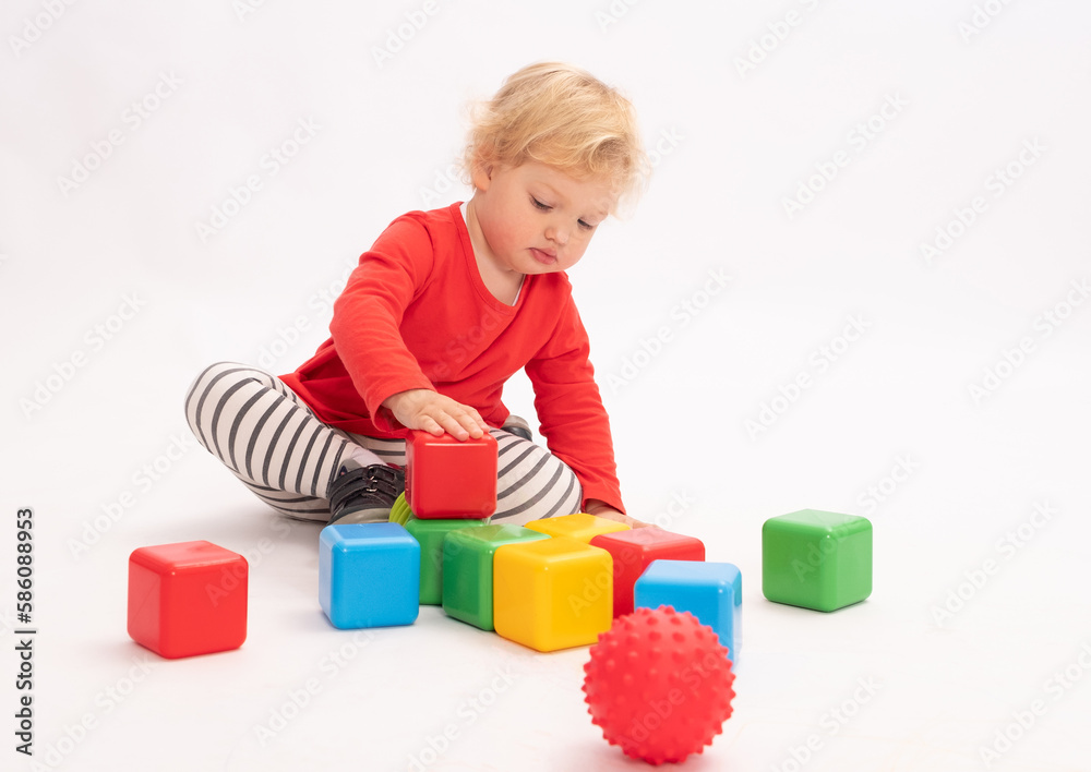 Cute little girl is building a tower from colorful cubes, white background Cute little girl is building a tower from colorful cubes, white background