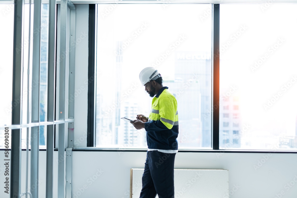 Engineering man working on tablet beside the window with white and blur building background.