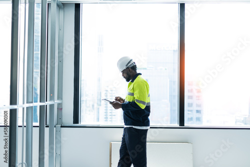 Engineering man working on tablet beside the window with white and blur building background.