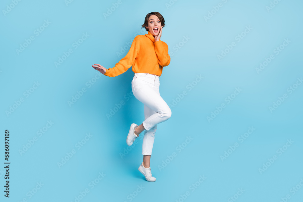 Full size photo of pretty young girl impressed astonished palm touch cheek dressed stylish orange look isolated on blue color background
