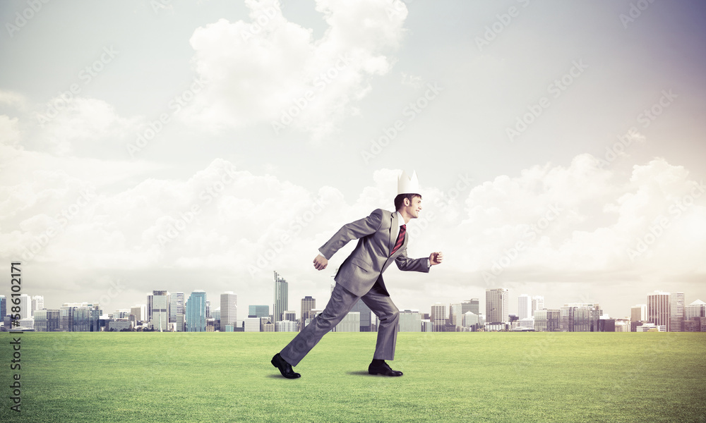 King businessman in elegant suit running on green grass and modern cityscape at background King businessman in elegant suit running on green grass and modern cityscape at background
