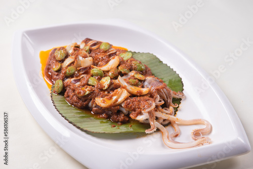 grilled bbq fresh whole seafood squid sooting octopus with spicy samba chilli sauce and petai smelly bean vegetables on banana leaf plate wood table asian halal food menu