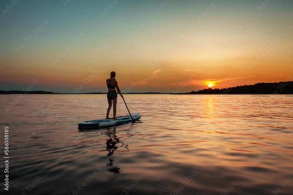 Silhouette of a female on the paddle boat at the sunset with copy space