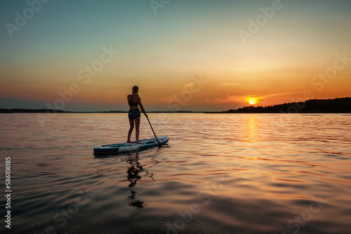 Silhouette of a female on the paddle boat at the sunset with copy space © rangizzz