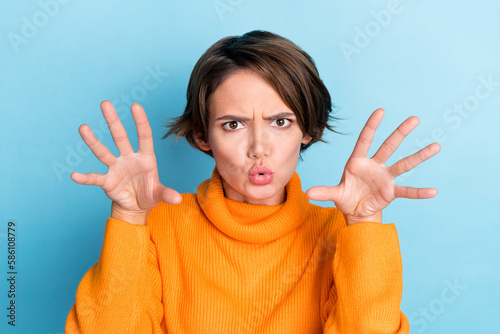 Photo portrait of attractive young woman raise hands frighten boo funky fooling wear trendy orange look isolated on blue color background