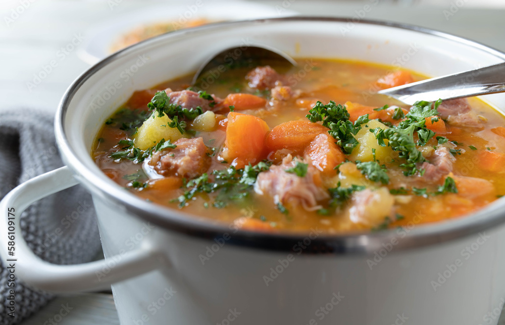 Stew with carrots, potatoes and smoked pork meat in a white enamel pot. Stew with carrots, potatoes and smoked pork meat in a white enamel pot.
