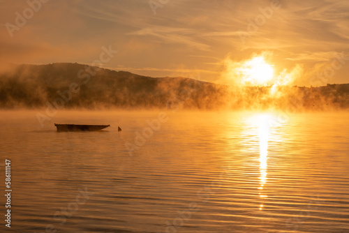 Mglisty wschód słońca nad jeziorem Żywieckim w bardzo ciepłej tonacji.