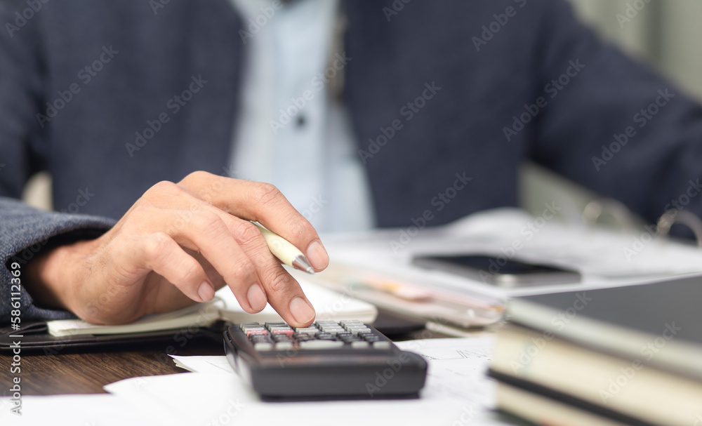 businessman using calculator and calculated finance report in office businessman using calculator and calculated finance report in office