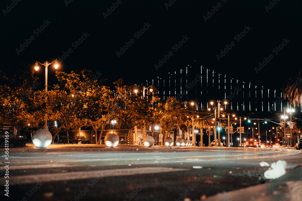 Night Photography of Streets in San Francisco. Streetlamps in the foreground, Oakland Bay Bridge in the background. Water.