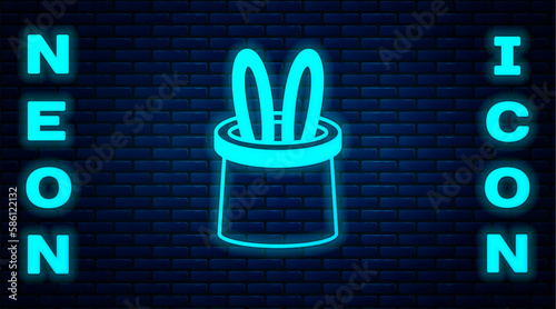 Glowing neon Magician hat and rabbit ears icon isolated on brick wall background. Magic trick. Mystery entertainment concept. Vector