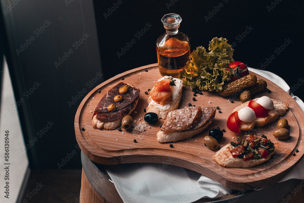 A wooden platter with a variety of food including meat, olives, olives, and olives.