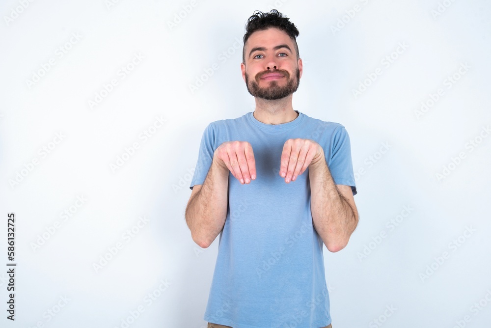 Young caucasian man wearing blue T-shirt over white background makes bunny paws and looks with innocent expression plays with her little kid Young caucasian man wearing blue T-shirt over white background makes bunny paws and looks with innocent expression plays with her little kid